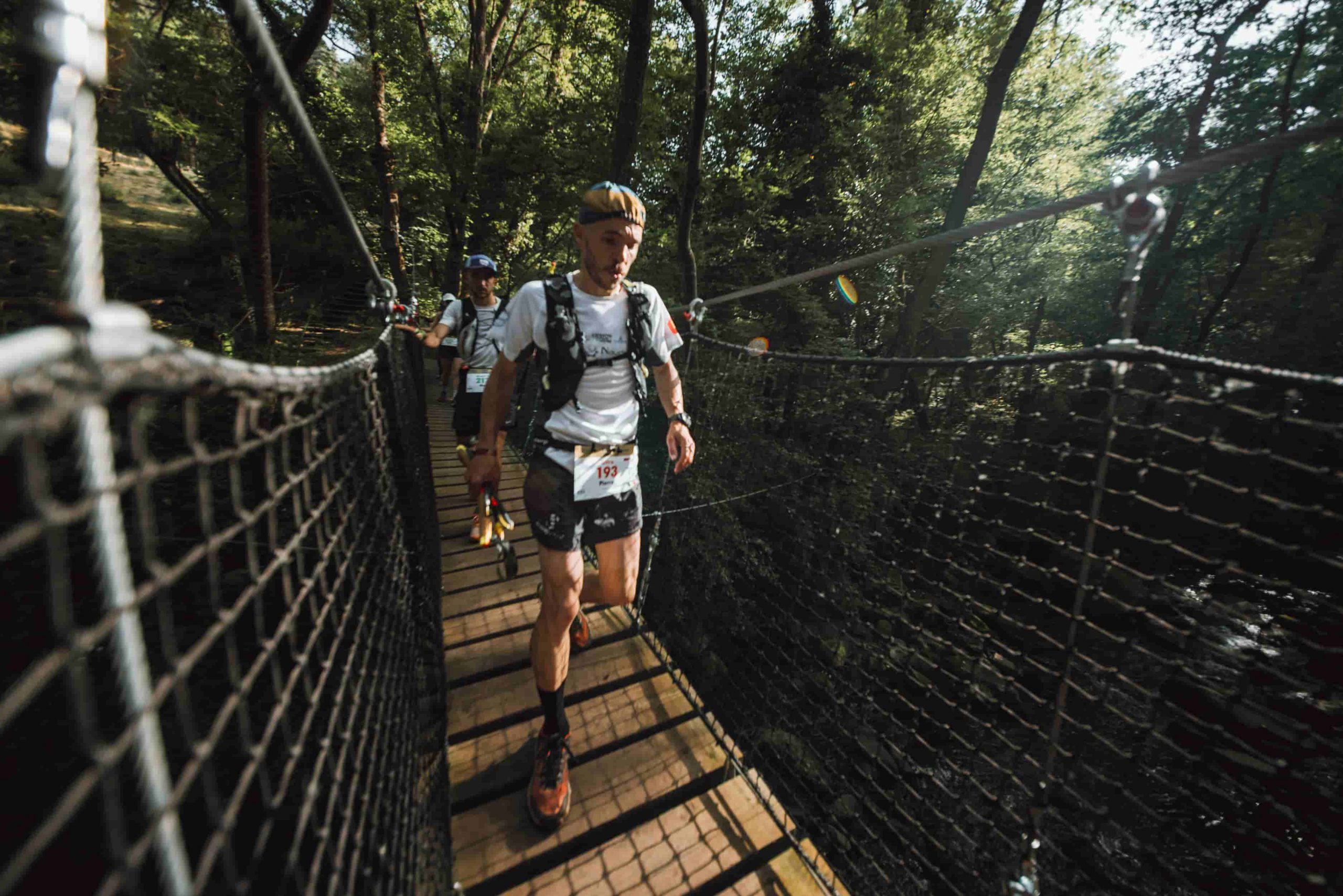 Des coureurs sur un pont suspendu lors du Trail du Saint-Jacques by UTMB.